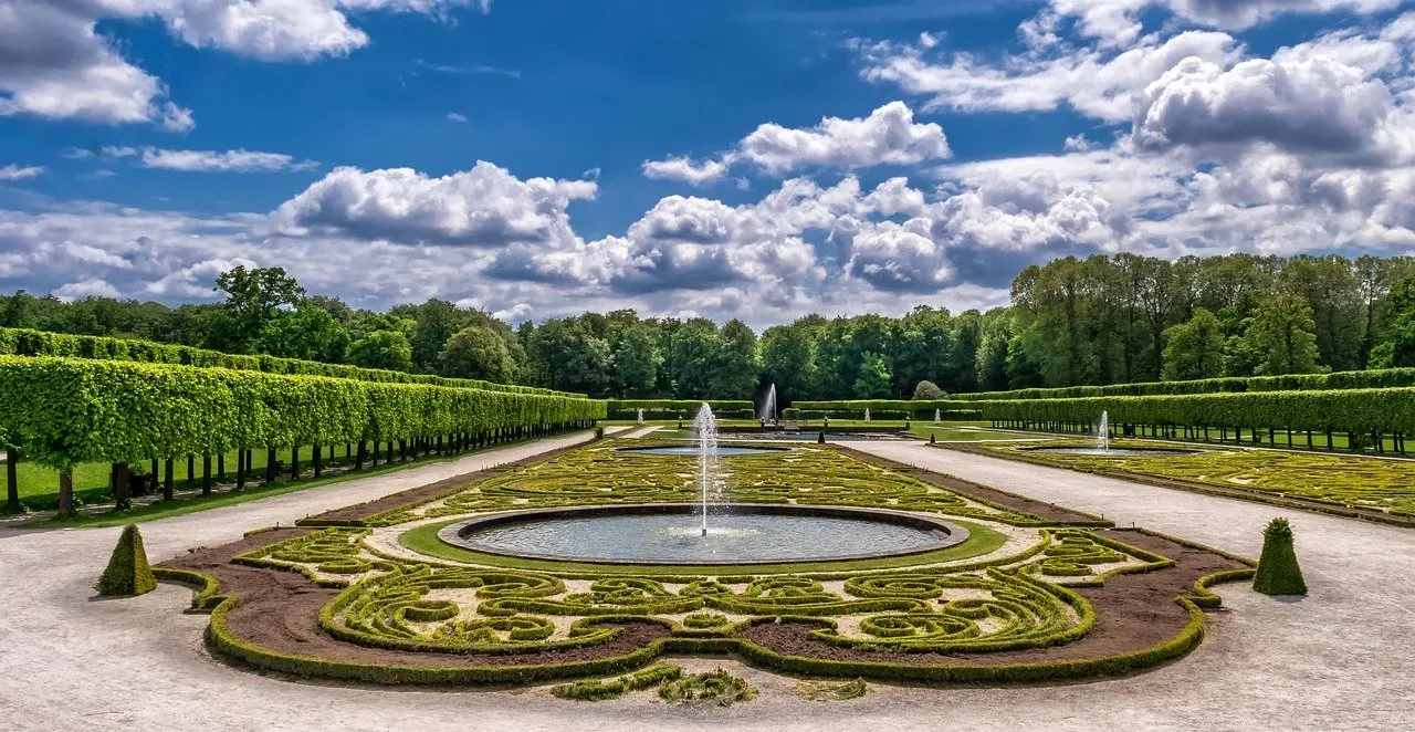 Formal angelegter Barockgarten mit Springbrunnen, geschnittenen Hecken und Baumreihen.