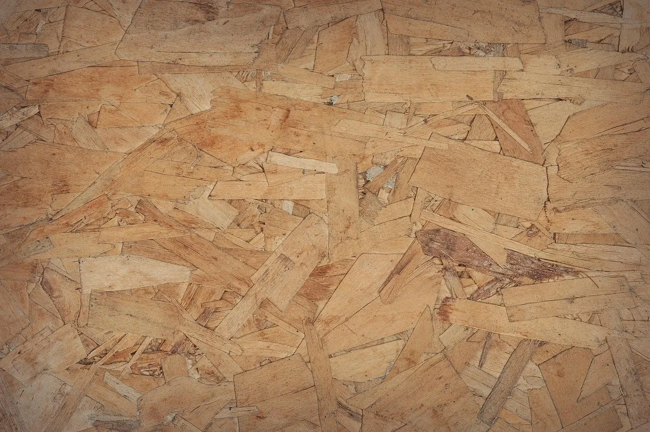 Nahaufnahme einer hellbraunen Spanplatte aus großen, unregelmäßig verpressten Holzspänen mit sichtbaren Kanten.
